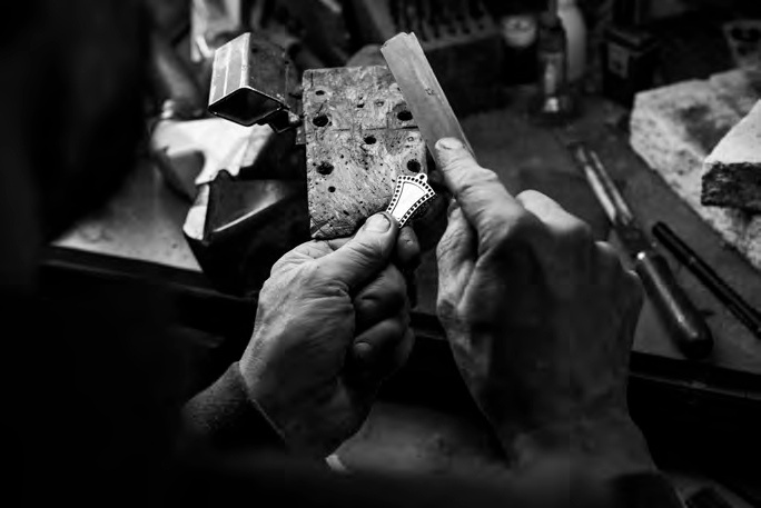 Bijutier lucrând manual la o piesă metalică în atelier